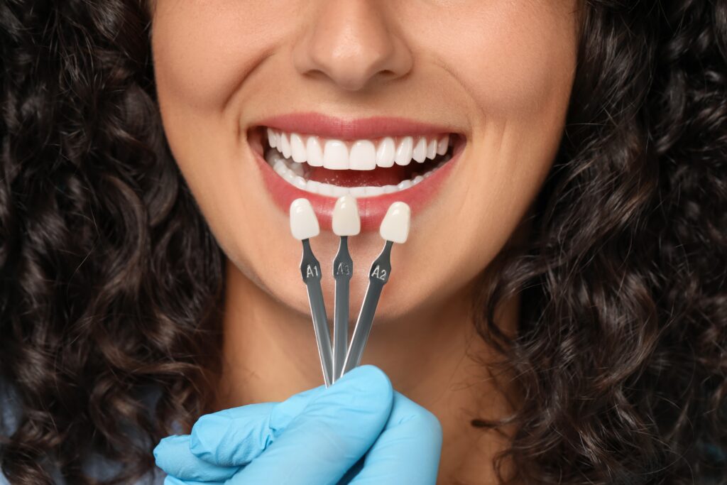 Doctor checking young woman’s teeth color for Dental Crowns LaFollette closeup